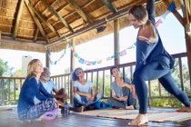 Female instructor demonstrating side angle pose in hut during yoga retreat — Stock Photo