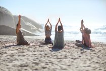 Ruhige Menschen im Kreis meditieren während des Yoga-Retreats am sonnigen Strand — Stockfoto