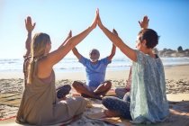 Група, що з'єднує руки в колі на сонячному пляжі під час відступу йоги — стокове фото