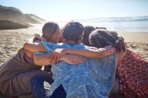 Group hugging in circle on sunny beach during yoga retreat — Stock Photo