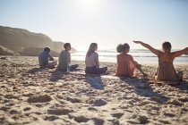 Gruppe sitzt auf Yogamatten am sonnigen Strand während des Yoga-Retreats — Stockfoto
