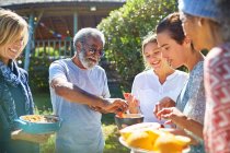 Друзья наслаждаются здоровой пищей снаружи солнечной хижины во время йоги отступления — стоковое фото