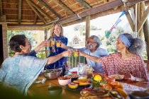 Friends toasting orange juice glasses at breakfast in hut during yoga retreat — Stock Photo