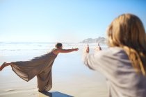 Frau praktiziert Krieger 3 posiert am sonnigen Strand während Yoga-Retreat — Stockfoto