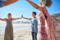 Women joining hands in circle on sunny beach during yoga retreat — Stock Photo