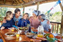 Happy friends hugging, enjoying healthy meal in hut during yoga retreat — Stock Photo