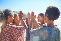 Grupo de pé em círculo com as mãos apertadas na praia ensolarada durante retiro de ioga — Fotografia de Stock