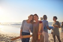 Retrato mãe feliz e filha com tapetes de ioga na praia ensolarada durante retiro de ioga — Fotografia de Stock