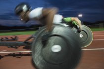 Atleti paraplegici che sfrecciano lungo la pista sportiva in gara su sedia a rotelle di notte — Foto stock