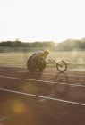 Determinado jovem atleta paraplégico do sexo masculino acelerando ao longo da pista de esportes na corrida em cadeira de rodas — Fotografia de Stock