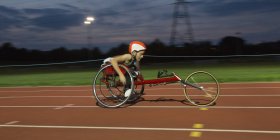 Решительная девочка-парализованная спортсменка, мчащаяся по спортивной трассе в гонке на инвалидных колясках — стоковое фото