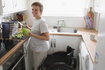 Портрет впевнено молода жінка з інвалідного крісла, приготування їжі в квартирі-кухня — стокове фото