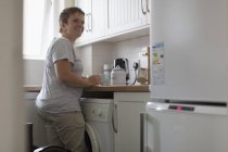 Усміхаючись молода жінка готується чай у квартирі-кухня — стокове фото
