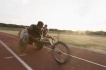 Determined young male paraplegic athlete speeding along sports track in wheelchair race — Stock Photo