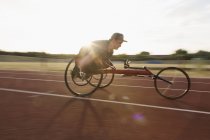 Визначений хлопчик-підліток паралельний спортсмен, що перевищує швидкість вздовж спортивної траси в гонці на інвалідних візках — стокове фото