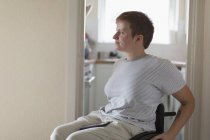 Задумчивая молодая женщина в инвалидной коляске дома — стоковое фото