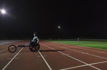 Ritratto fiducioso giovane atleta paraplegico donna formazione per gara in sedia a rotelle su pista sportiva — Foto stock