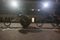 Atleta paraplégico acelerando ao longo da pista de esportes durante a corrida em cadeira de rodas — Fotografia de Stock