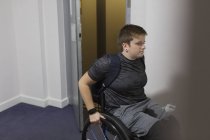 Jovem mulher em cadeira de rodas saindo do elevador — Fotografia de Stock