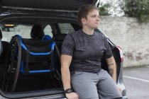 Mujer joven y segura con silla de ruedas en la parte trasera del coche - foto de stock