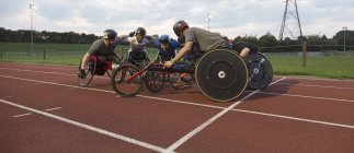 Entschlossene querschnittsgelähmte Sportler, die sich auf der Sportbahn auf Rollstuhlrennen vorbereiten — Stockfoto