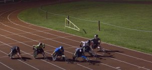 Querschnittsgelähmte rasen nachts bei Rollstuhlrennen über Sportstrecke — Stockfoto