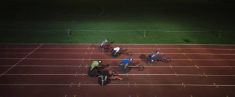 Paraplegic athletes racing along sports track in wheelchair race in night — Stock Photo