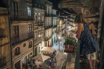 Frau steht auf Balkon, blickt auf verzierte Architektur, Porto, portugal — Stockfoto