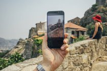 Людина особистої точки зору з камерою телефону фотографування жінка на кам'яною стіною, Монсанто, Португалія — стокове фото