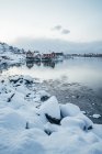 Vistas panorámicas nevadas pueblo de pescadores frente al mar, Reine, Islas Lofoten, Noruega - foto de stock
