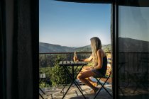 Женщина отдыхает, пьет пиво на солнечном летнем балконе — стоковое фото