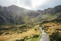 Woman walking along craggy mountain trail, Snowdonia NP, Reino Unido — Fotografia de Stock