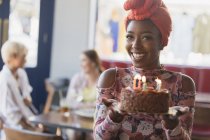 Ritratto sorridente, giovane donna fiduciosa che tiene la torta di compleanno con le candele — Foto stock