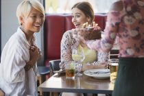 Excited young women friends celebrating birthday with cake in restaurant — Stock Photo