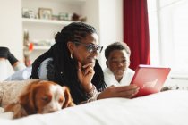 Бабуся і онук використовують цифровий планшет поруч зі сплячою собакою на ліжку — стокове фото