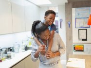 Playful mother and son piggybacking in kitchen — Stock Photo