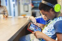 Junge mit Kopfhörern und digitalem Tablet spielt Videospiel — Stockfoto