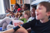 Багатоетнічна сім'я дивиться фільм і їсть попкорн — стокове фото