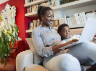 Mother and son  using laptop on living room sofa — Stock Photo