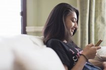 Tween menina mensagens de texto com telefone inteligente no sofá — Fotografia de Stock