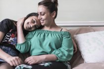 Прихильна мати і дочка обіймаються на дивані у вітальні — стокове фото