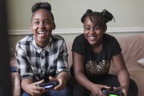 Друзья-подростки играют в видеоигры на диване в гостиной — стоковое фото