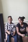 Happy tween girl friends playing video game in living room — Stock Photo
