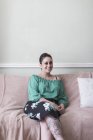 Portrait smiling, confident woman with tattoos on living room sofa — Stock Photo