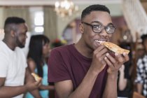 Портрет улыбающегося подростка, поедающего пиццу с семьей — стоковое фото