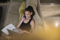 Frau telefoniert mit Smartphone und Laptop auf Sofa — Stockfoto