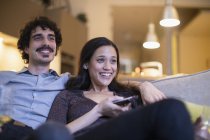 Felice coppia guardando la tv sul divano — Foto stock