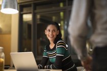 Усміхнена жінка використовує ноутбук вдома вночі — стокове фото