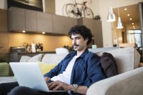 Mann benutzt Laptop auf Wohnzimmersofa — Stockfoto