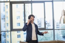 Sorrindo homem falando no telefone inteligente no apartamento urbano — Fotografia de Stock